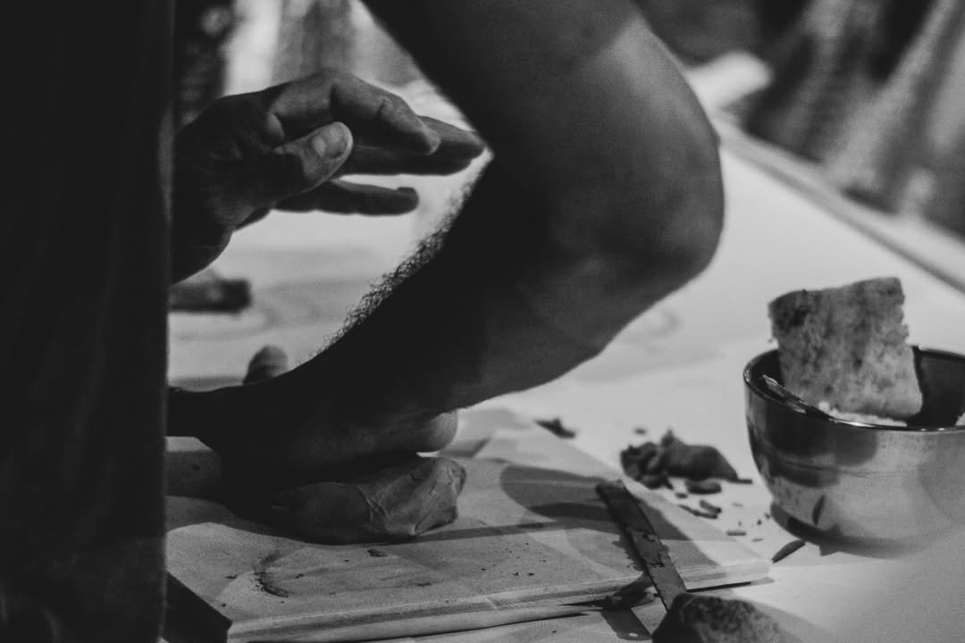 Unas manos trabajando una pieza de cerámica sobre una tabla de madera