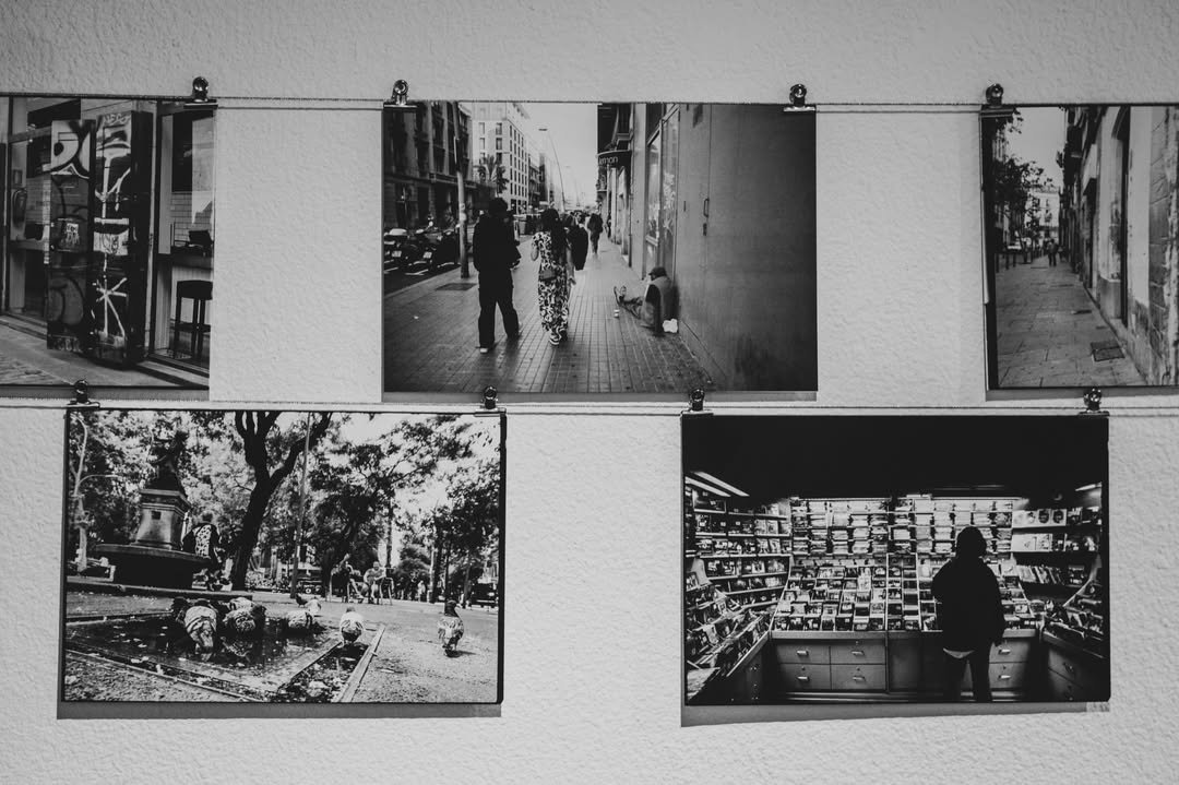 Copias de fotografía analógica colgadas con pinzas de un hilo, sobre una pared blanca